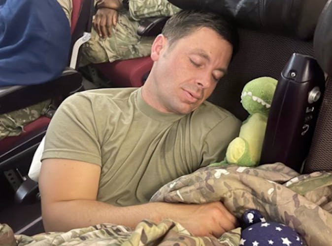 David, militaire, dort avec le doudou dinosaure de son fils.