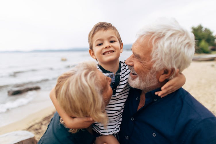 Un enfant avec ses grands-parents en bord de plage.