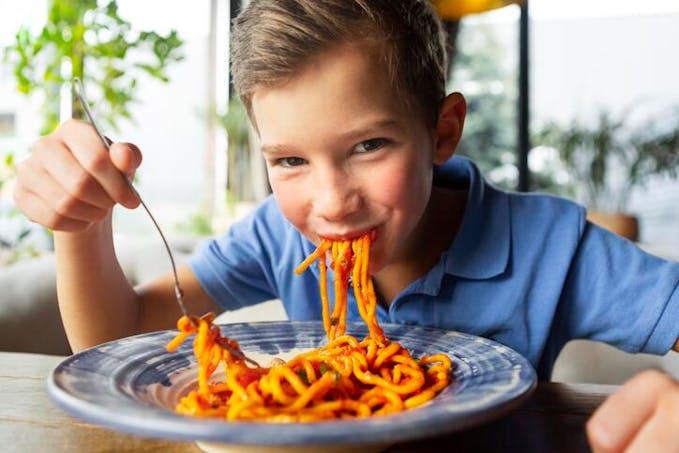 garçon dévorant des spaghettis