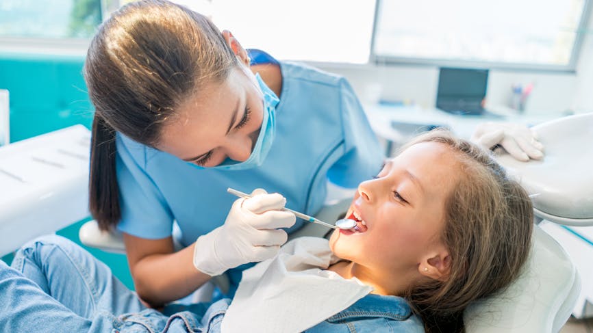 Une jeune fille se fait examiner par une dentiste. 
