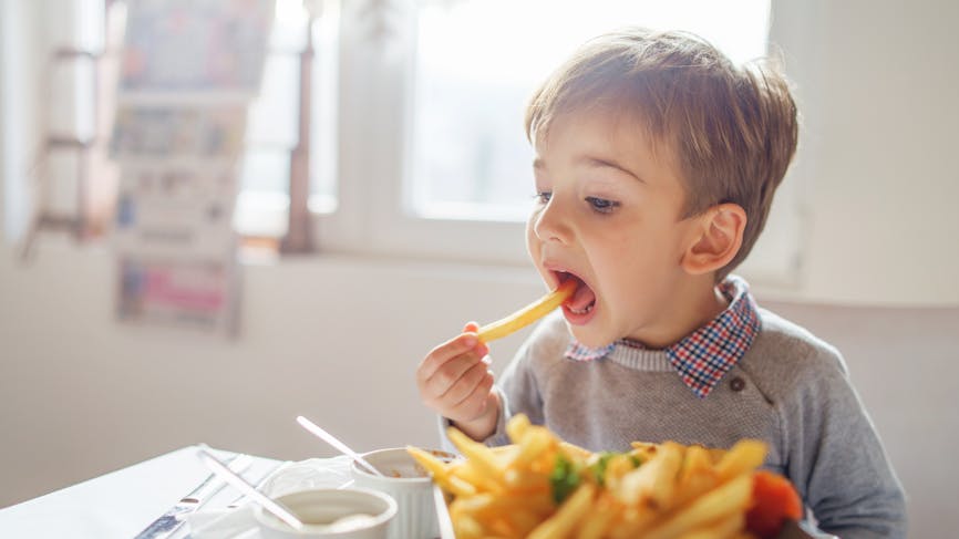 Petit garçon qui mange une frite. 