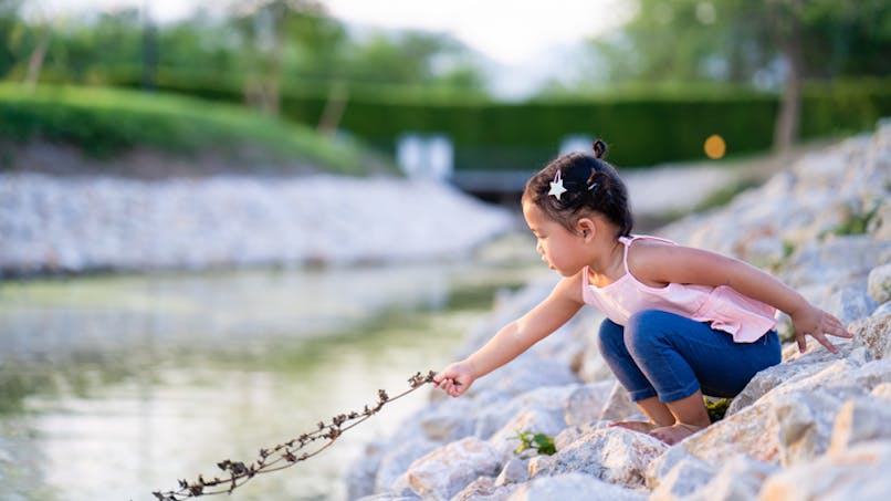 petite fille jouant près d'un ruisseau