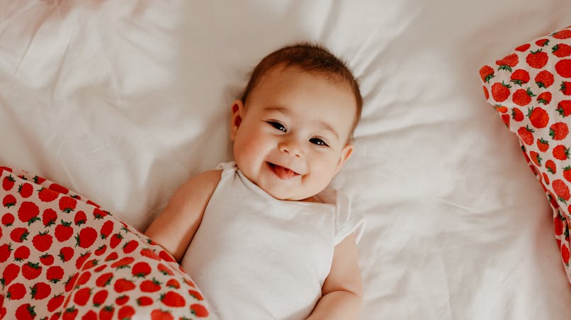 Bébé souriant, couverture motif fraise