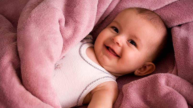 Bébé souriant, couverture rose en polaire