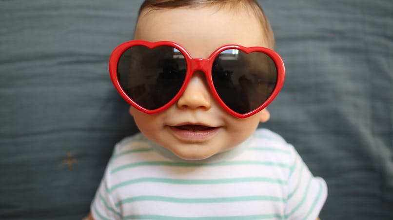 bébé avec lunette de soleil en forme de coeur rouge
