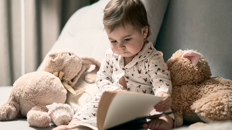 bébé lit un livre avec doudou