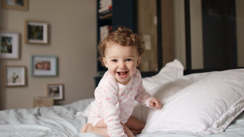 enfant souriant sur un lit