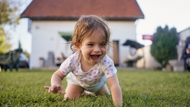 Bébé marche à quatre patte dans l'herbe