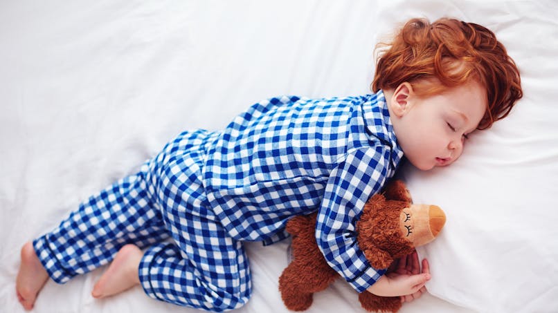 enfant roux qui dort dans un pyjama bleu à carreaux