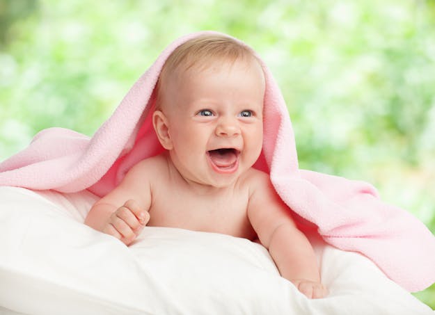bébé riant, peignoir sur la tête