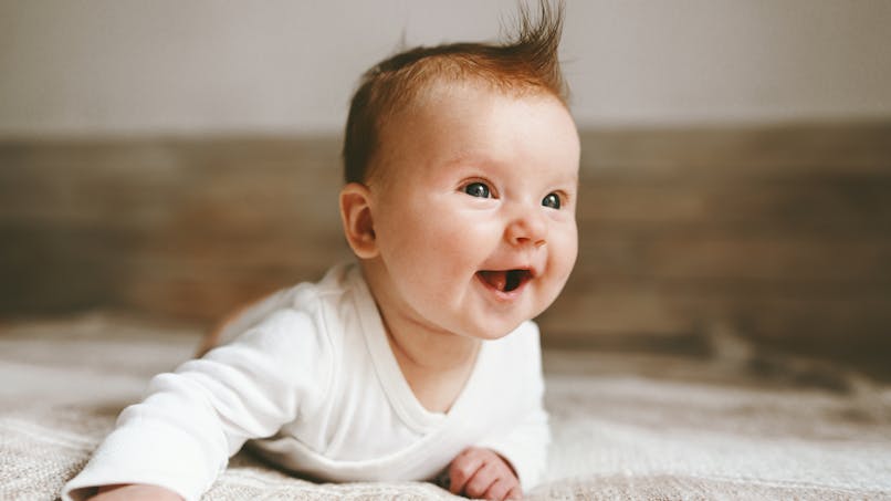 Bébé à plat ventre souriant et cheveux en l'air