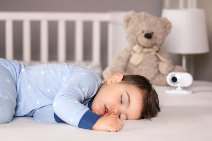 enfant brun dormant sur le côté dans pyjama bleu