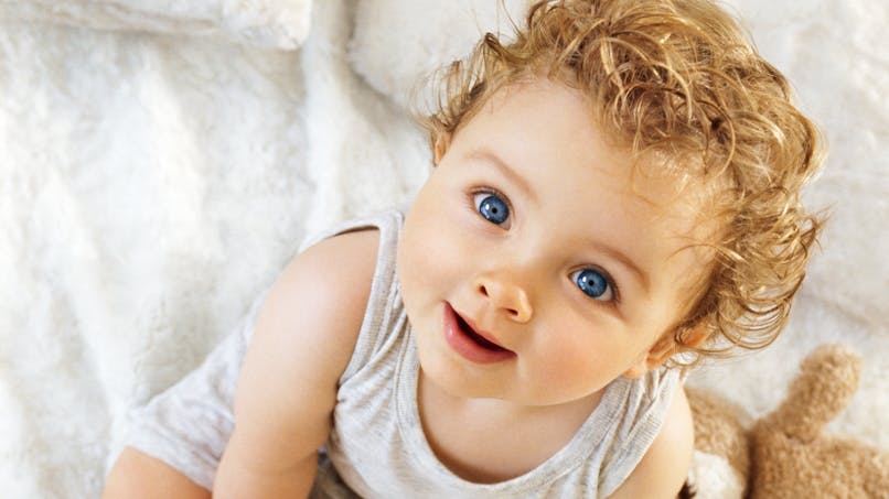 enfant regard objectif, yeux bleus et cheveux bouclés