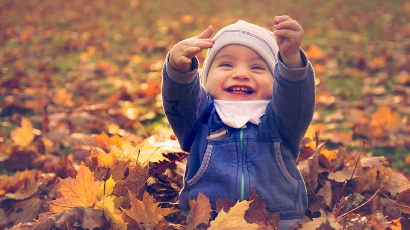 enfant jouant dans les feuilles d'automne
