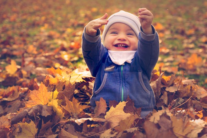 enfant jouant dans les feuilles d'automne