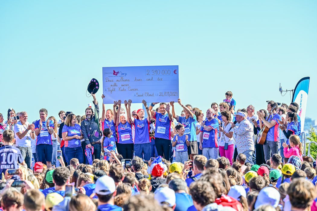Les participants de la course "Enfants Sans Cancer" lèvent le chèque de 2 310 000 euros collectés. 