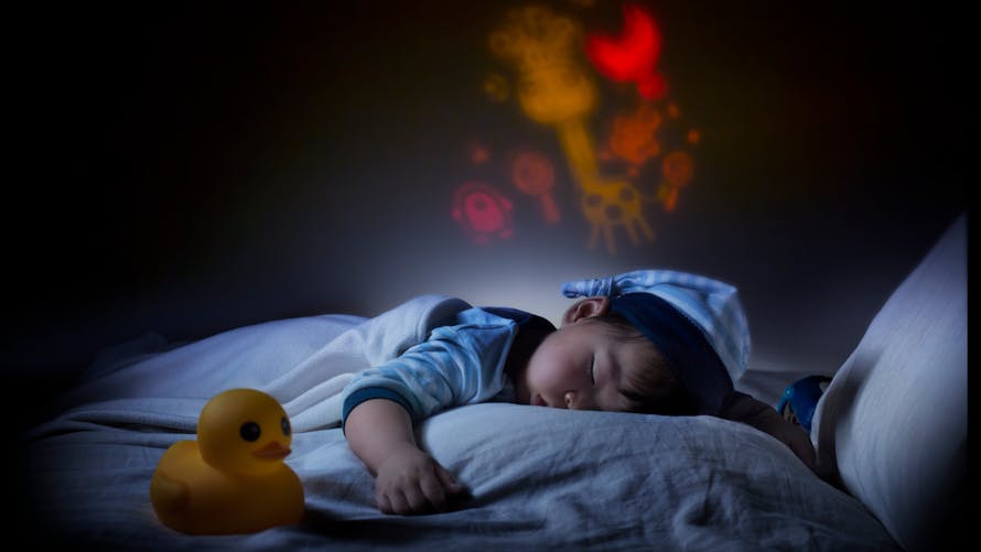 bébé dormant dans son lit avec une lumière projetée sur le mur