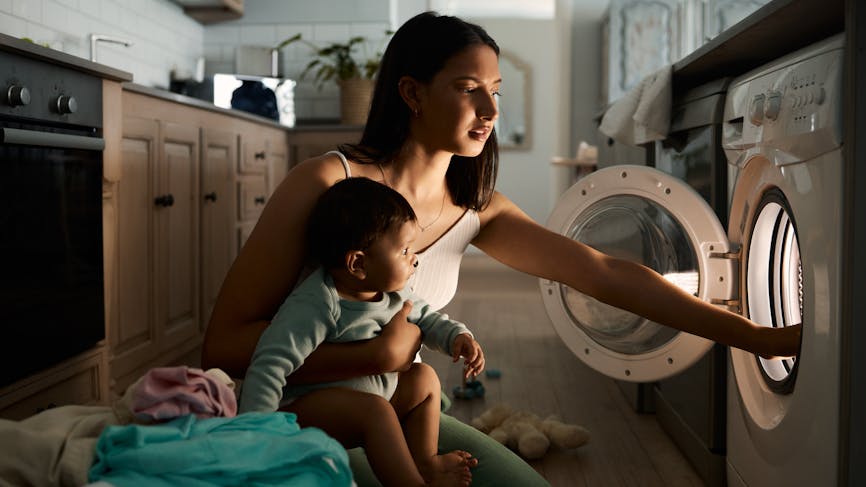 Une mère qui fait la lessive avec son bébé 