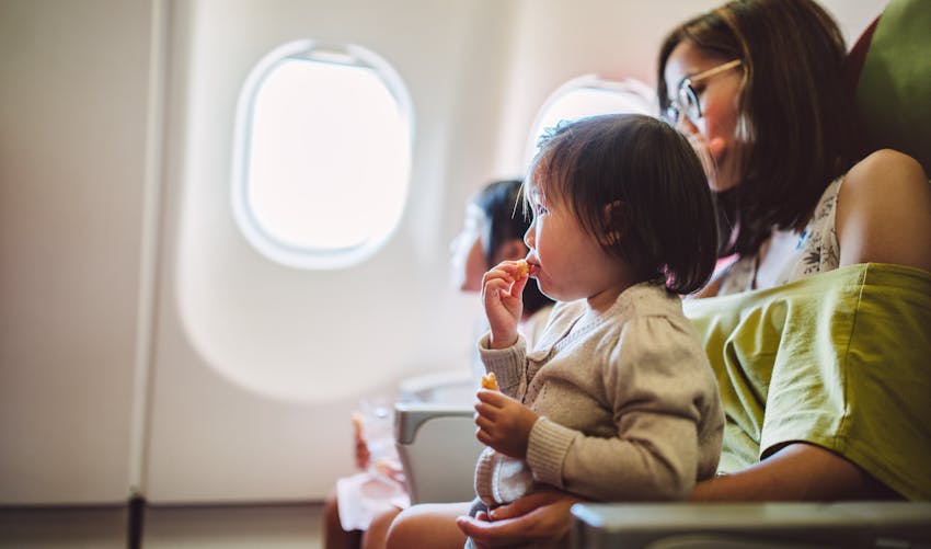 Une femme porte son enfant sur ses genoux dans un avion