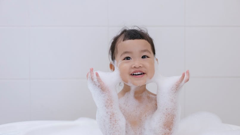 enfant fille dans un bain plein de mousse