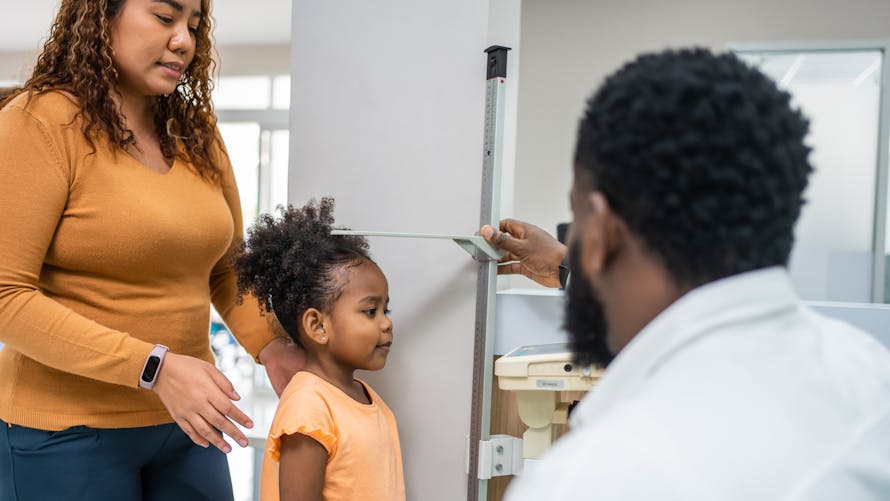 Un médecin qui mesure une enfant. 