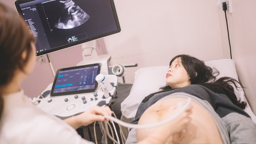 Une professionnelle de santé réalise une échographie avec femme enceinte attentive