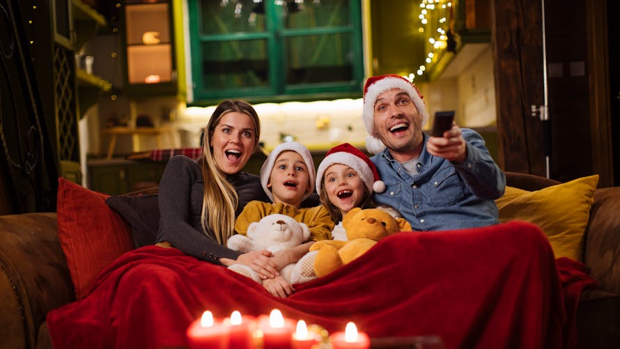 Famille nucléaire sur un canapé regardant un film à Noël