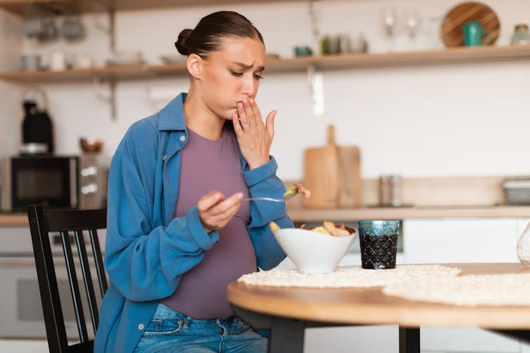 Une femme enceinte est prise de nausée alors qu'elle mange dans sa cuisine
