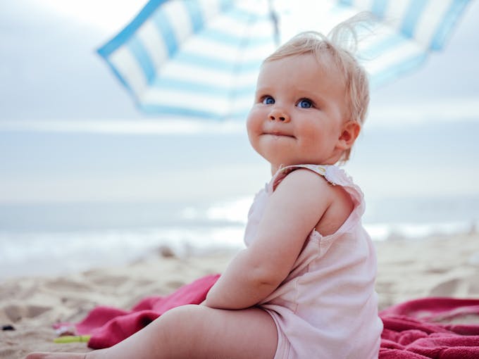 Une petite fille est assise sur la plage. 