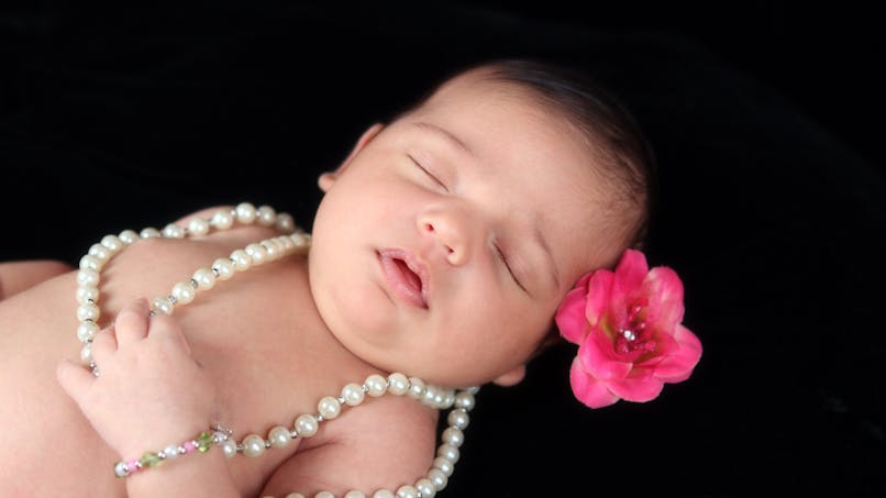 bébé fille qui dort avec fleur rose dans les cheveux