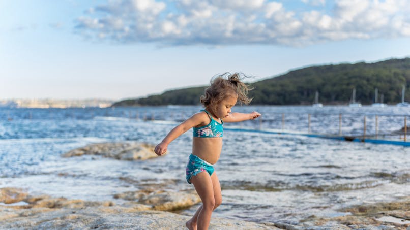 petite fille sur la plage en maillot de bain bleu
