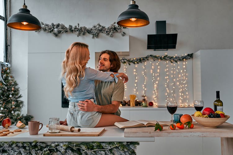 Un couple amoureux flirte dans la cuisine, près du sapin de Noël