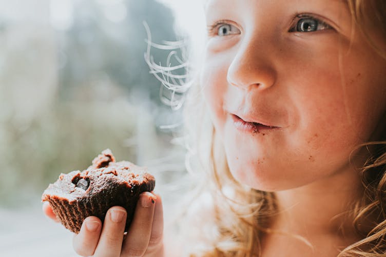 petite fille qui mange un gâteau au chocolat