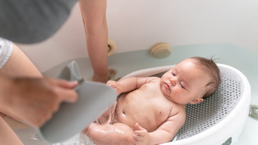 Un bébé prend un bain. 