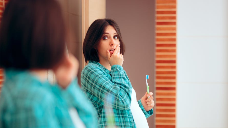 Une femme enceinte est surprise par son reflet dans le miroir - concept de nez de grossesse