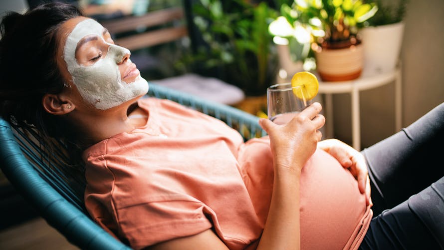 Une femme enceinte prend soin d'elle avec un masque pour la peau du visage