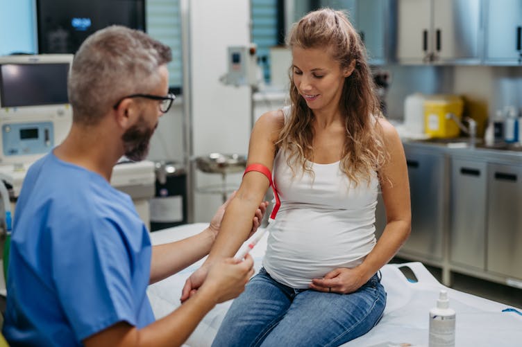 Une jeune femme enceinte s'apprête à avoir une prise de sang - dépistage prééclampsie grossesse